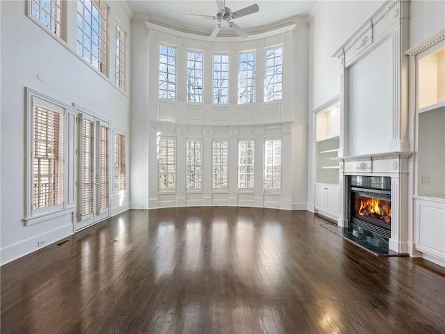 unfurnished living room with built in shelves, ornamental molding, a healthy amount of sunlight, and a fireplace