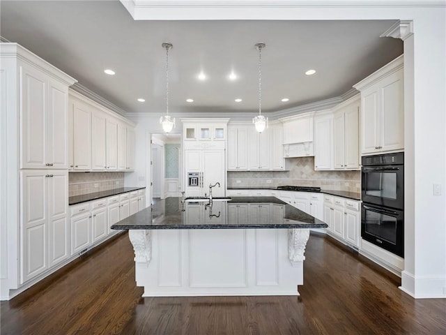 kitchen with pendant lighting, an island with sink, white cabinets, black double oven, and paneled built in refrigerator