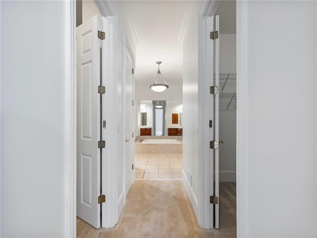 hall with crown molding and light carpet