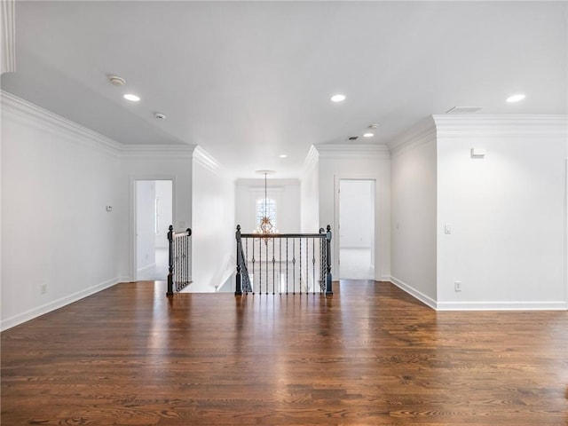 empty room featuring crown molding, dark hardwood / wood-style flooring, and a chandelier