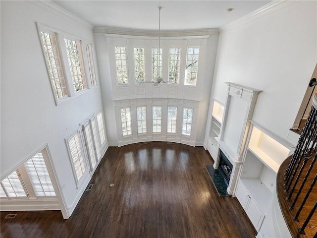 living room featuring crown molding, dark hardwood / wood-style floors, ceiling fan, a premium fireplace, and a high ceiling