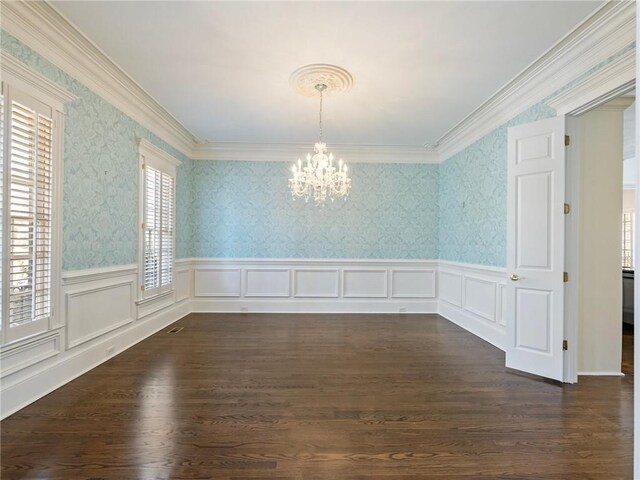 spare room featuring dark wood-type flooring, ornamental molding, and a chandelier