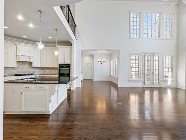 kitchen with decorative light fixtures, a center island with sink, white cabinets, and decorative backsplash