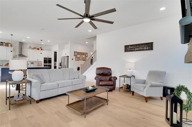 living area featuring light wood finished floors, ceiling fan, stairs, and recessed lighting