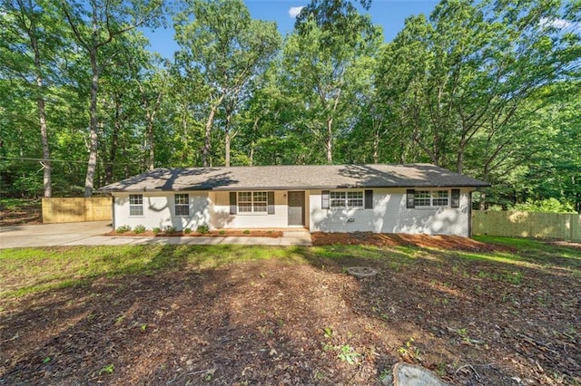 ranch-style home with fence, covered porch, brick siding, and driveway