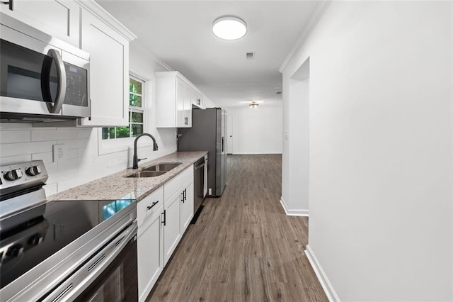 kitchen with appliances with stainless steel finishes, a sink, backsplash, dark wood finished floors, and white cabinetry