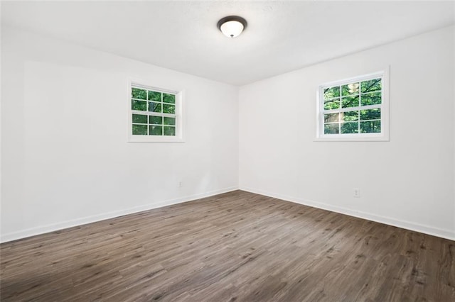 unfurnished room featuring plenty of natural light, dark wood finished floors, and baseboards
