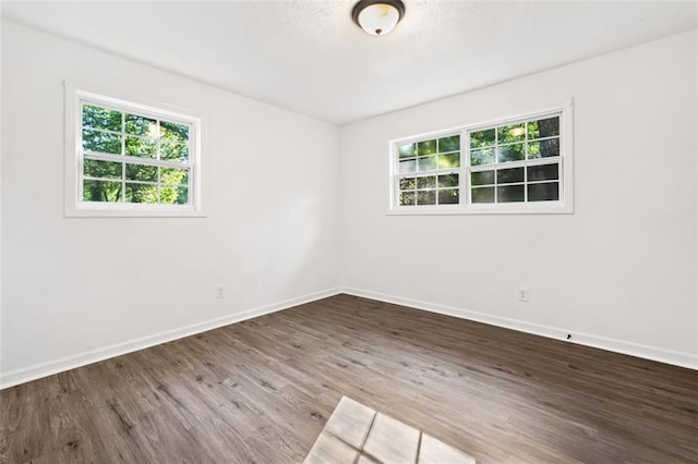 spare room featuring healthy amount of natural light, wood finished floors, and baseboards