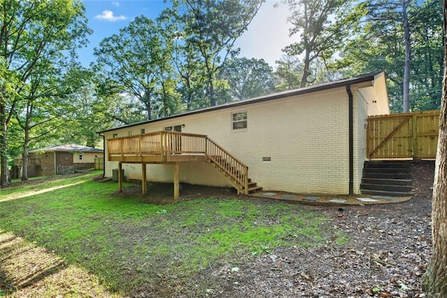 back of property featuring stairway, a wooden deck, and brick siding
