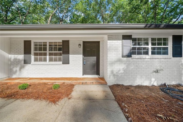 property entrance featuring brick siding and a porch