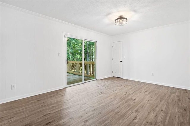 spare room featuring crown molding, wood finished floors, and baseboards
