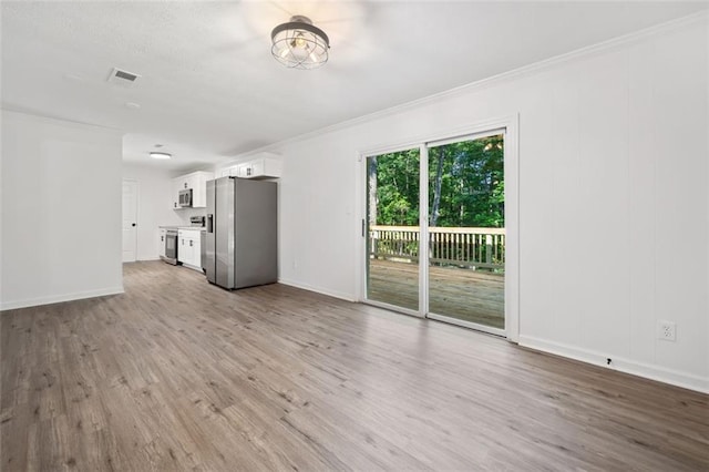 unfurnished living room featuring wood finished floors, ornamental molding, and baseboards