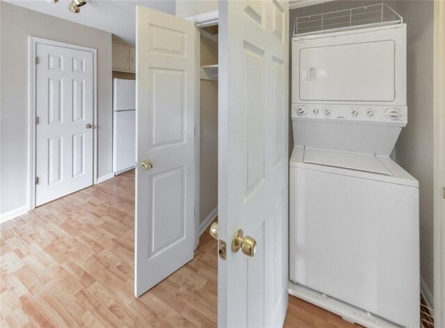 washroom with stacked washer and clothes dryer and light wood-type flooring