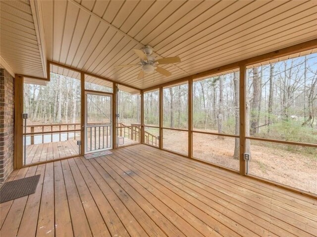 unfurnished sunroom featuring wooden ceiling, a healthy amount of sunlight, and ceiling fan