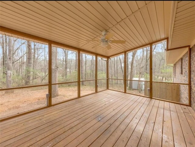 unfurnished sunroom with ceiling fan, wooden ceiling, and a wealth of natural light