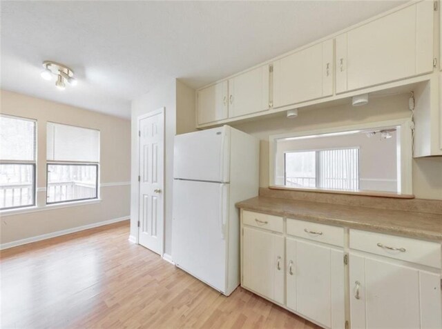 kitchen with white cabinets, white refrigerator, and light wood-type flooring