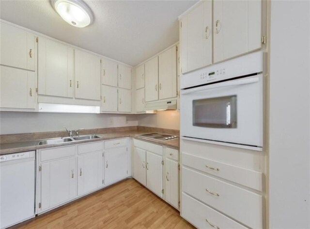 kitchen with light wood-type flooring, white appliances, sink, and white cabinets