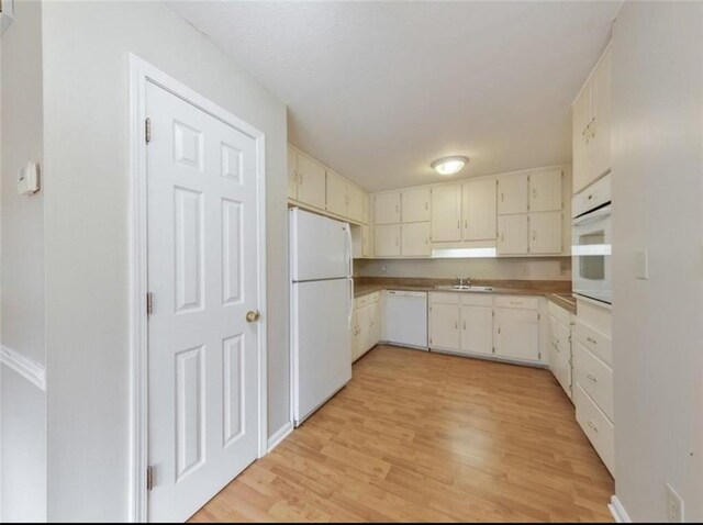 kitchen with light wood-type flooring, white appliances, white cabinets, and sink