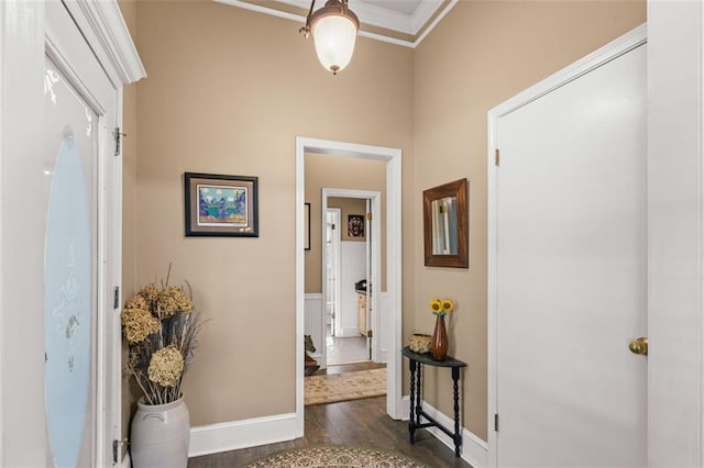 hall with dark wood-style floors, crown molding, and baseboards