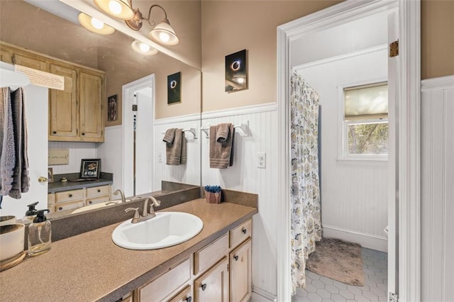 bathroom featuring a shower with shower curtain, tile patterned floors, vanity, and wainscoting