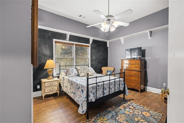 bedroom with ceiling fan, wood finished floors, and baseboards