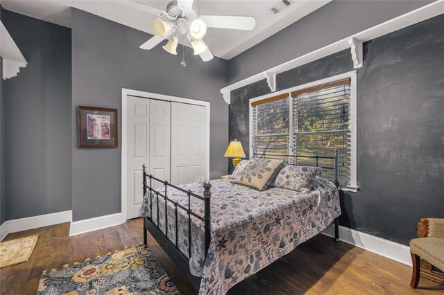 bedroom featuring a closet, visible vents, a ceiling fan, wood finished floors, and baseboards