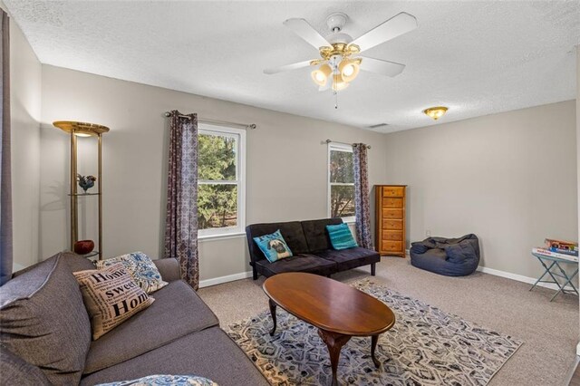 living area featuring carpet floors, ceiling fan, baseboards, and a textured ceiling