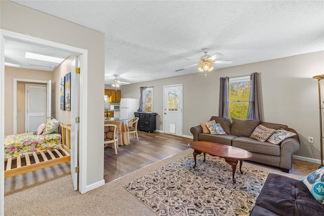 living room featuring ceiling fan, a textured ceiling, and baseboards