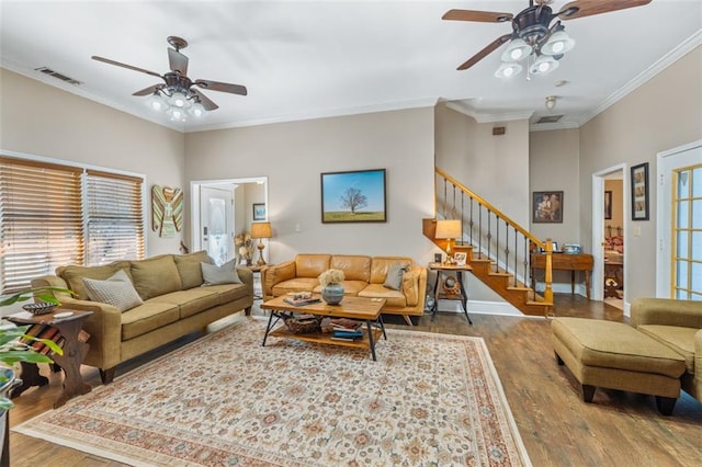 living area with visible vents, ornamental molding, ceiling fan, wood finished floors, and stairs