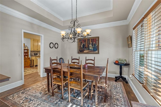 dining area featuring a tray ceiling, baseboards, and wood finished floors