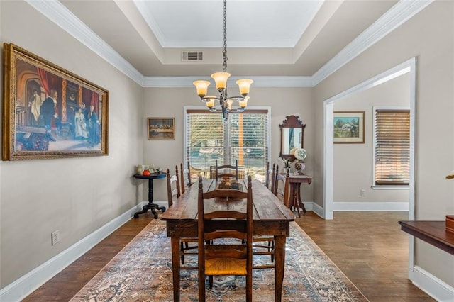 dining space with dark wood-style floors, a tray ceiling, a chandelier, and baseboards