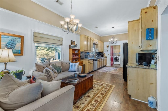 living room with an inviting chandelier, visible vents, dark wood-style flooring, and washer / dryer