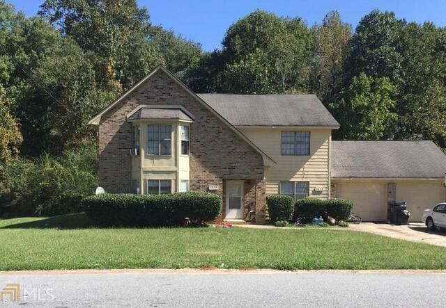 view of front of property featuring a front yard, concrete driveway, brick siding, and a garage