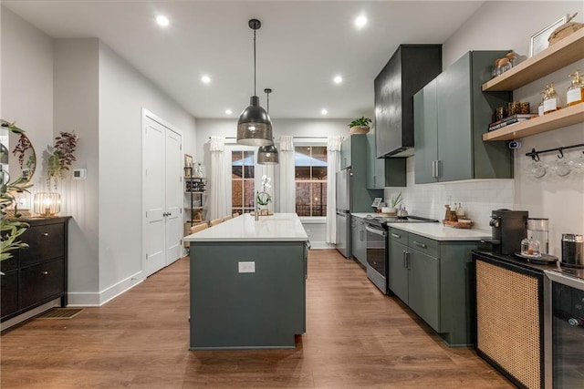 kitchen featuring pendant lighting, hardwood / wood-style flooring, an island with sink, appliances with stainless steel finishes, and beverage cooler