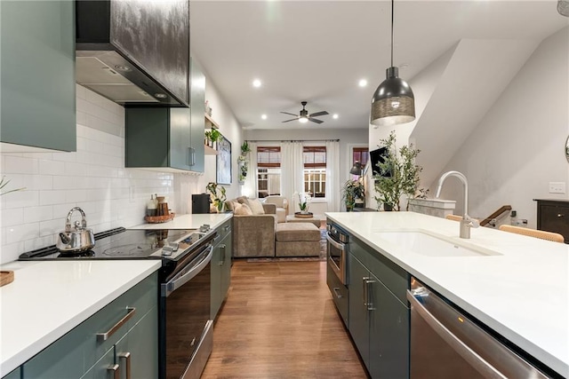 kitchen with sink, stainless steel appliances, dark hardwood / wood-style flooring, decorative light fixtures, and custom exhaust hood