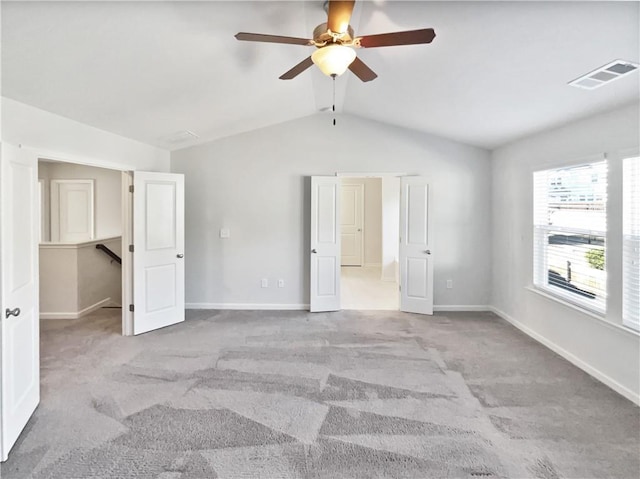 unfurnished bedroom featuring lofted ceiling, light colored carpet, a spacious closet, and ceiling fan