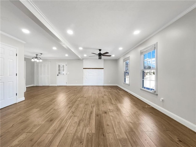 unfurnished living room with recessed lighting, ceiling fan with notable chandelier, wood finished floors, baseboards, and crown molding