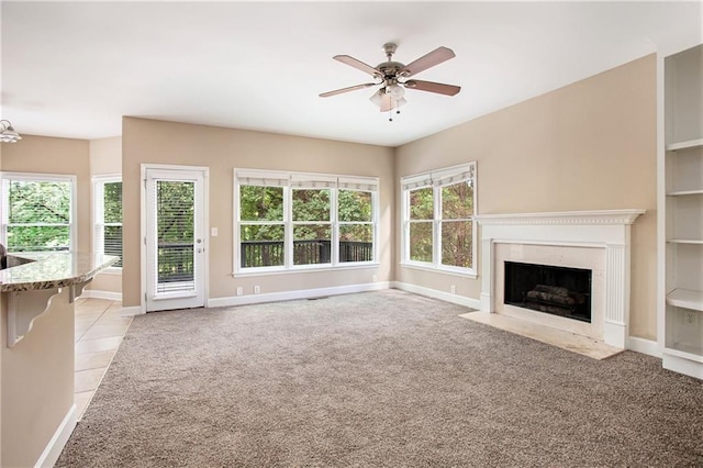 unfurnished living room featuring light carpet, ceiling fan, and a premium fireplace