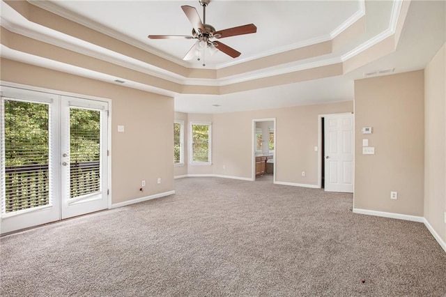 empty room with a tray ceiling, ceiling fan, french doors, and ornamental molding