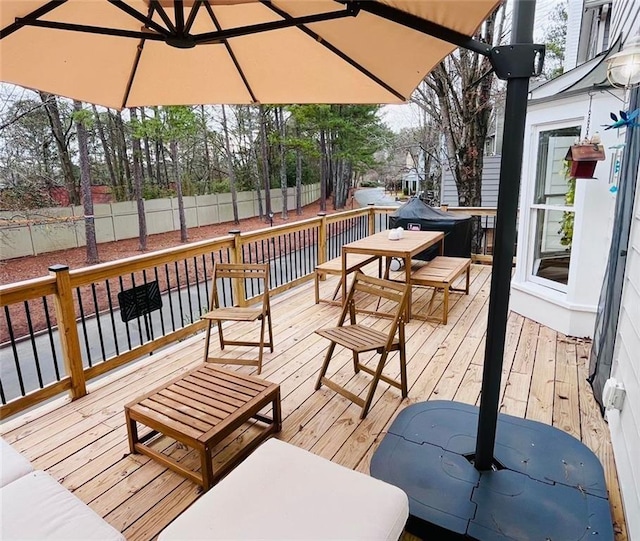 wooden terrace with outdoor dining space and fence