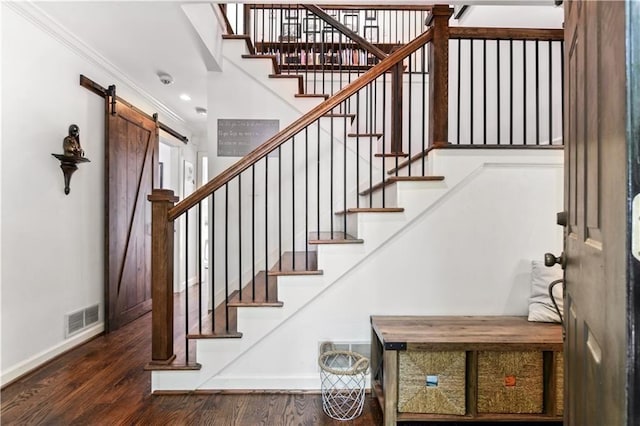 staircase featuring wood finished floors, visible vents, baseboards, and a barn door