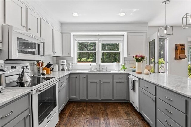 kitchen with white appliances, dark wood-style flooring, a sink, gray cabinetry, and backsplash