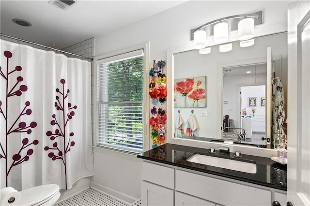 bathroom with toilet, a wealth of natural light, vanity, and visible vents