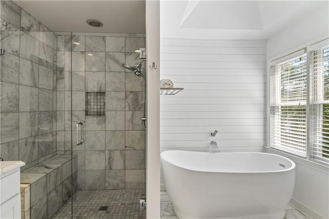 bathroom featuring marble finish floor, a soaking tub, a shower stall, and a wealth of natural light