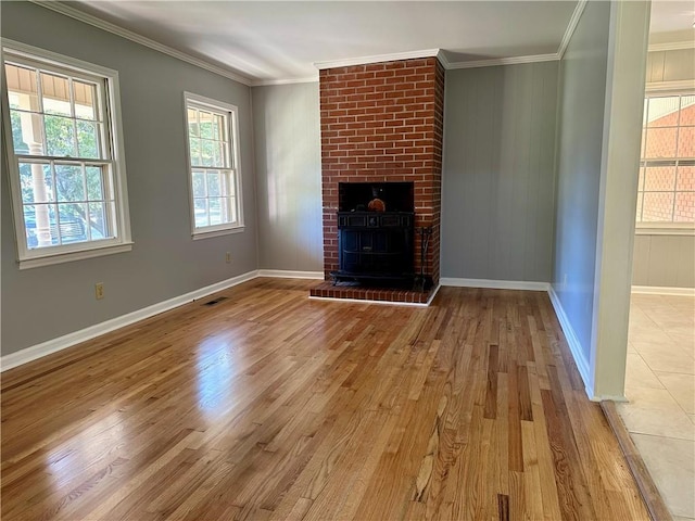 unfurnished living room featuring a fireplace, ornamental molding, and light wood-type flooring