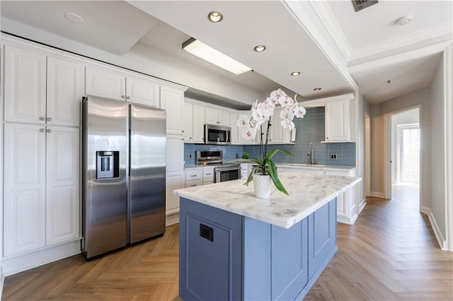 2161 Peachtree Rd NE Unit 907, Atlanta, GA 30309 - kitchen featuring appliances with stainless steel finishes, crown molding, white cabinetry, tasteful backsplash, and a center island