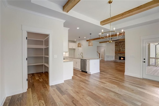 kitchen with hanging light fixtures, beamed ceiling, stainless steel dishwasher, white cabinets, and light hardwood / wood-style flooring