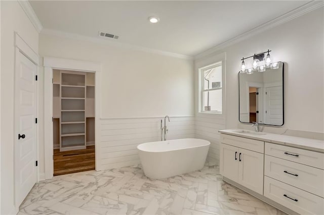 bathroom with a bathtub, ornamental molding, and vanity