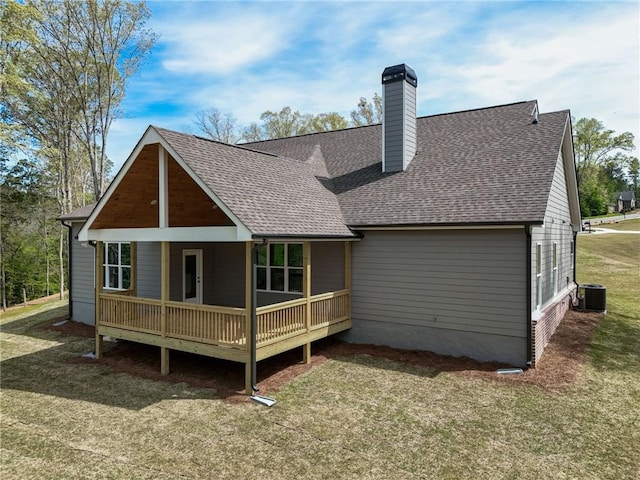 rear view of property featuring central AC and a lawn