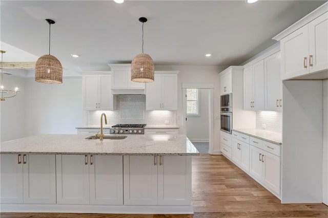 kitchen featuring decorative backsplash, hanging light fixtures, light wood-type flooring, white cabinets, and light stone counters